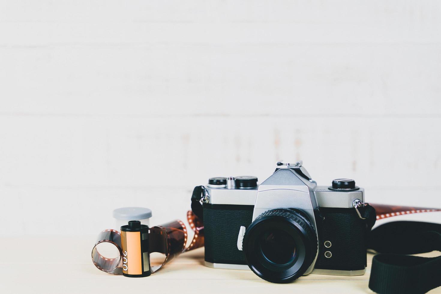 Old 35mm SLR film camera and a roll of film on wooden background. Flim photography concept. photo