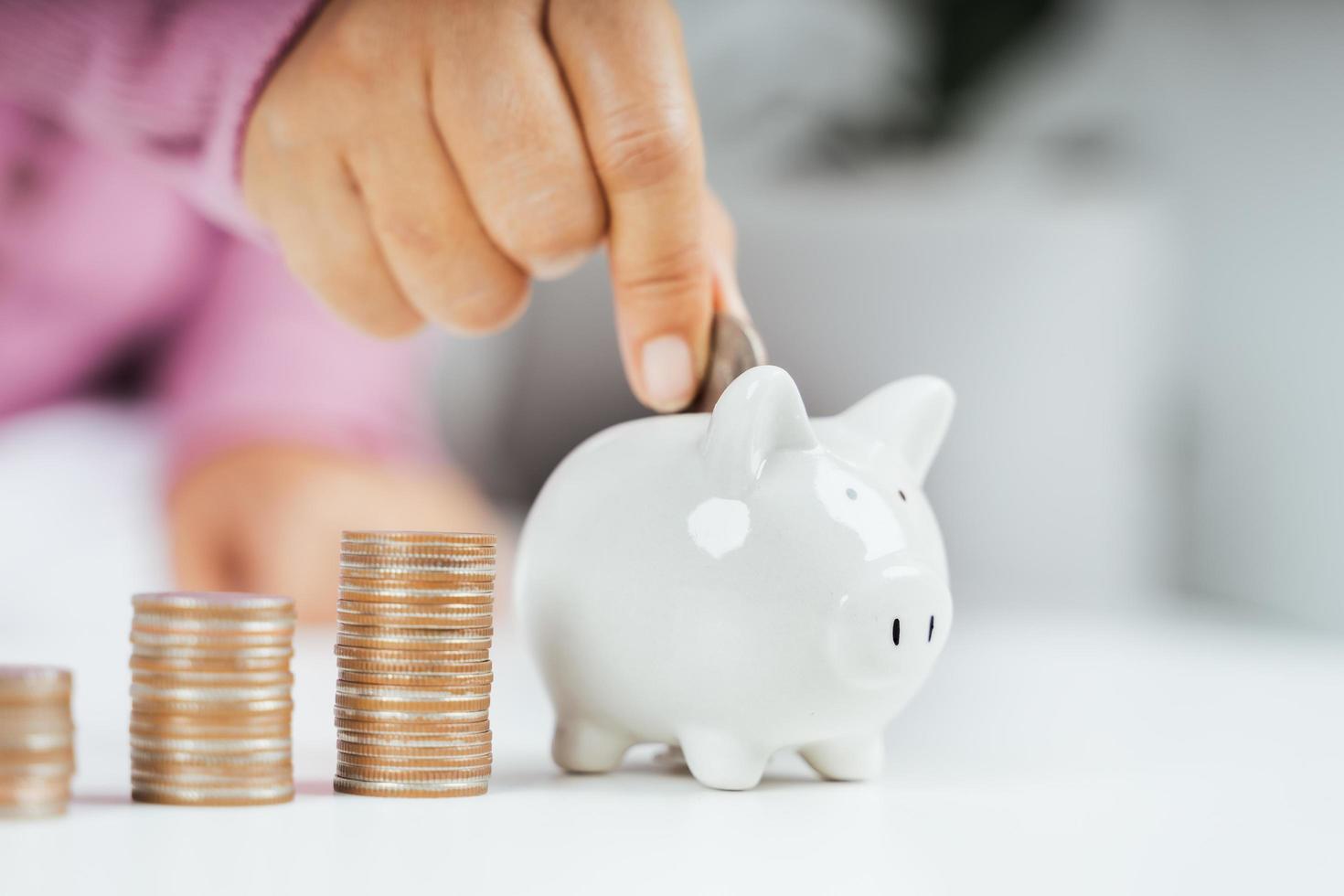 Closeup of business woman hand putting money coin into piggy bank for saving money. saving money and financial concept photo