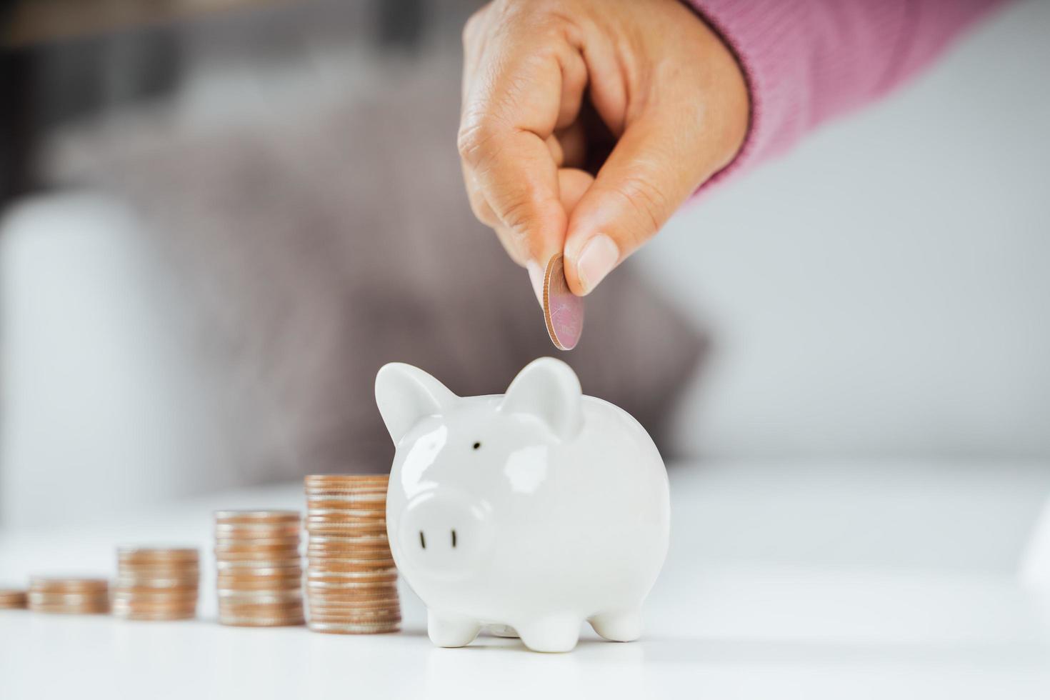 Closeup of business woman hand putting money coin into piggy bank for saving money. saving money and financial concept photo