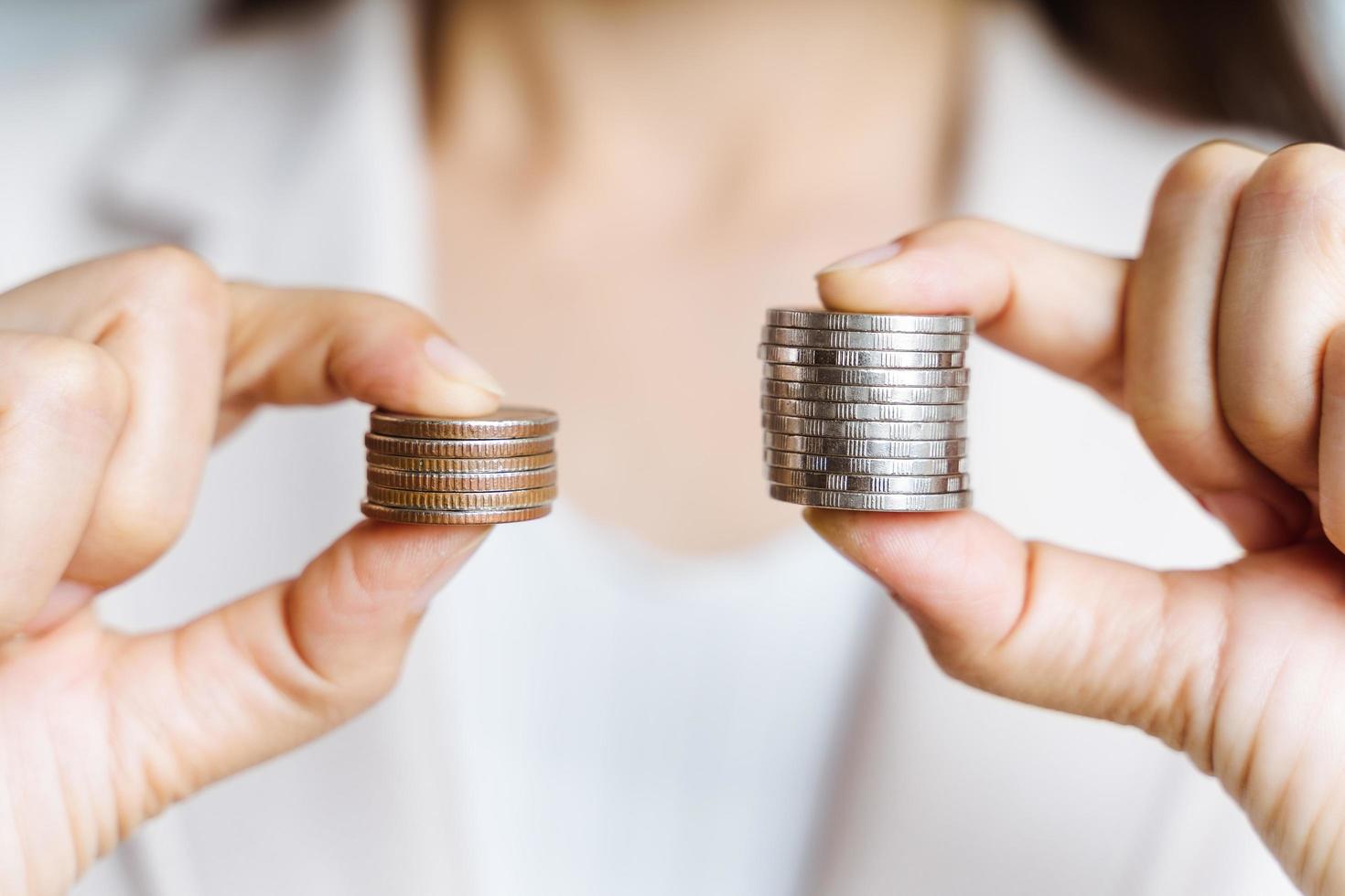 Hands compare two piles of coins of different sizes. photo