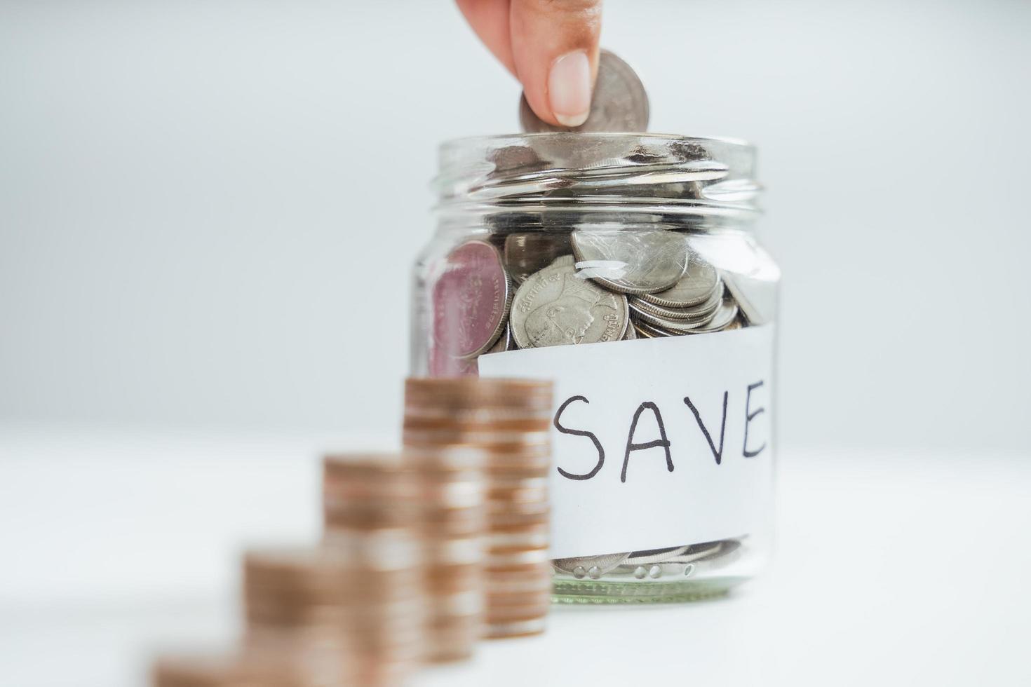 women hand putting money coin into glass jar for saving money. saving money and financial concept photo