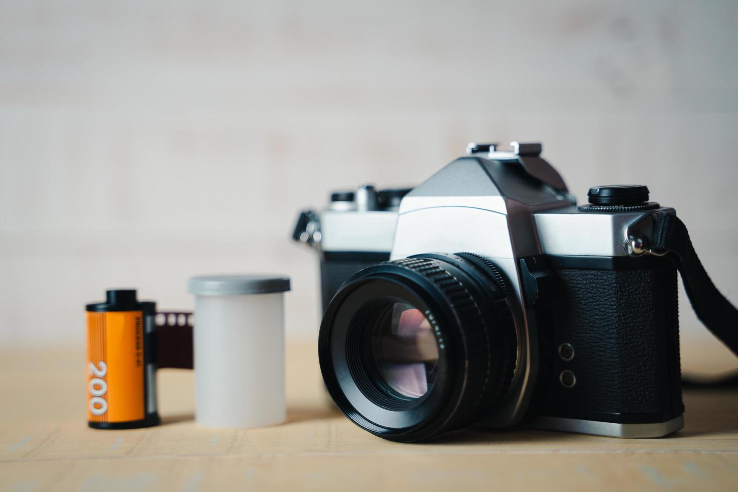 Old SLR film camera and a roll of film on wooden background. photo