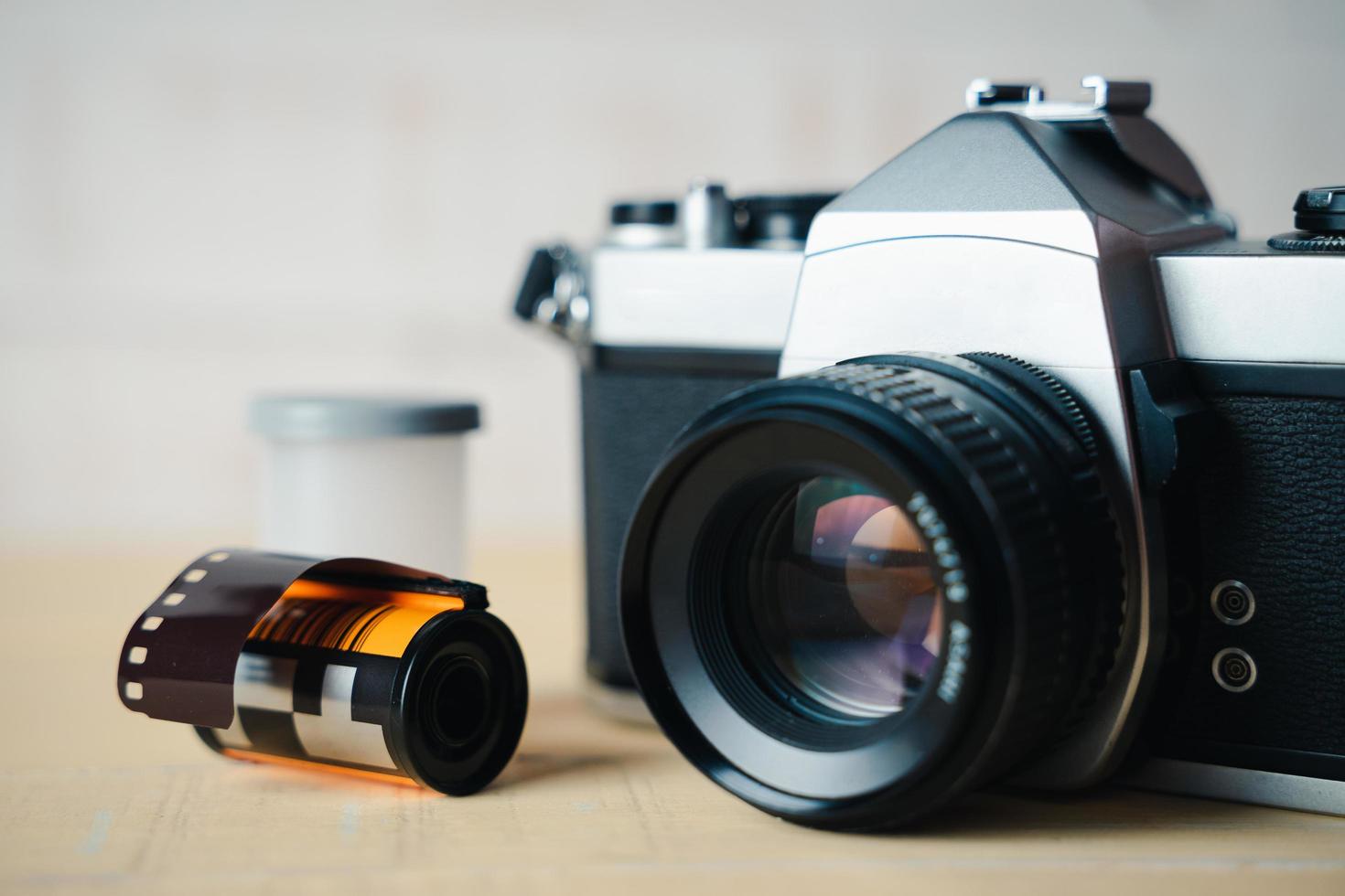 Old SLR film camera and a roll of film on wooden background. photo