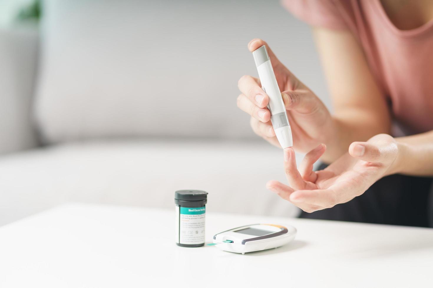 Asian woman using lancet on finger for checking blood sugar level by Glucose meter, Healthcare and Medical, diabetes, glycemia concept photo