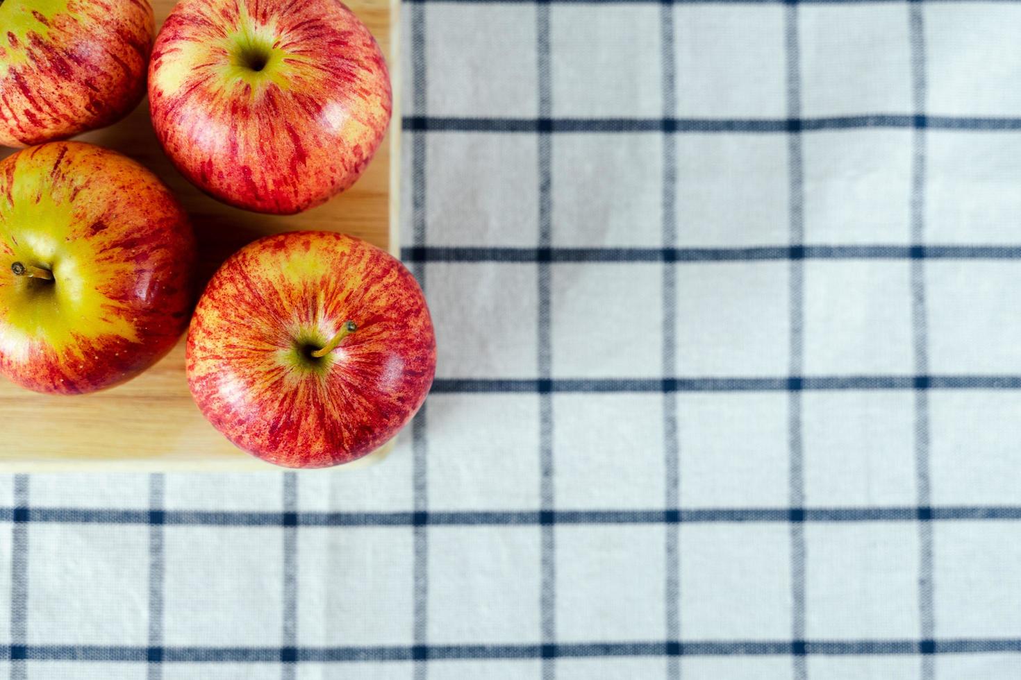 manzanas rojas frescas sobre tabla de cortar de madera y fondo de toalla. foto