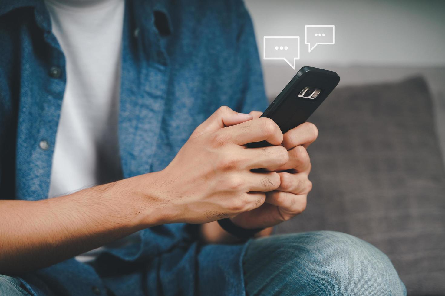 Young Asian man using smartphone typing, chatting conversation with pop up chat box icons. Social Network, technology concept photo