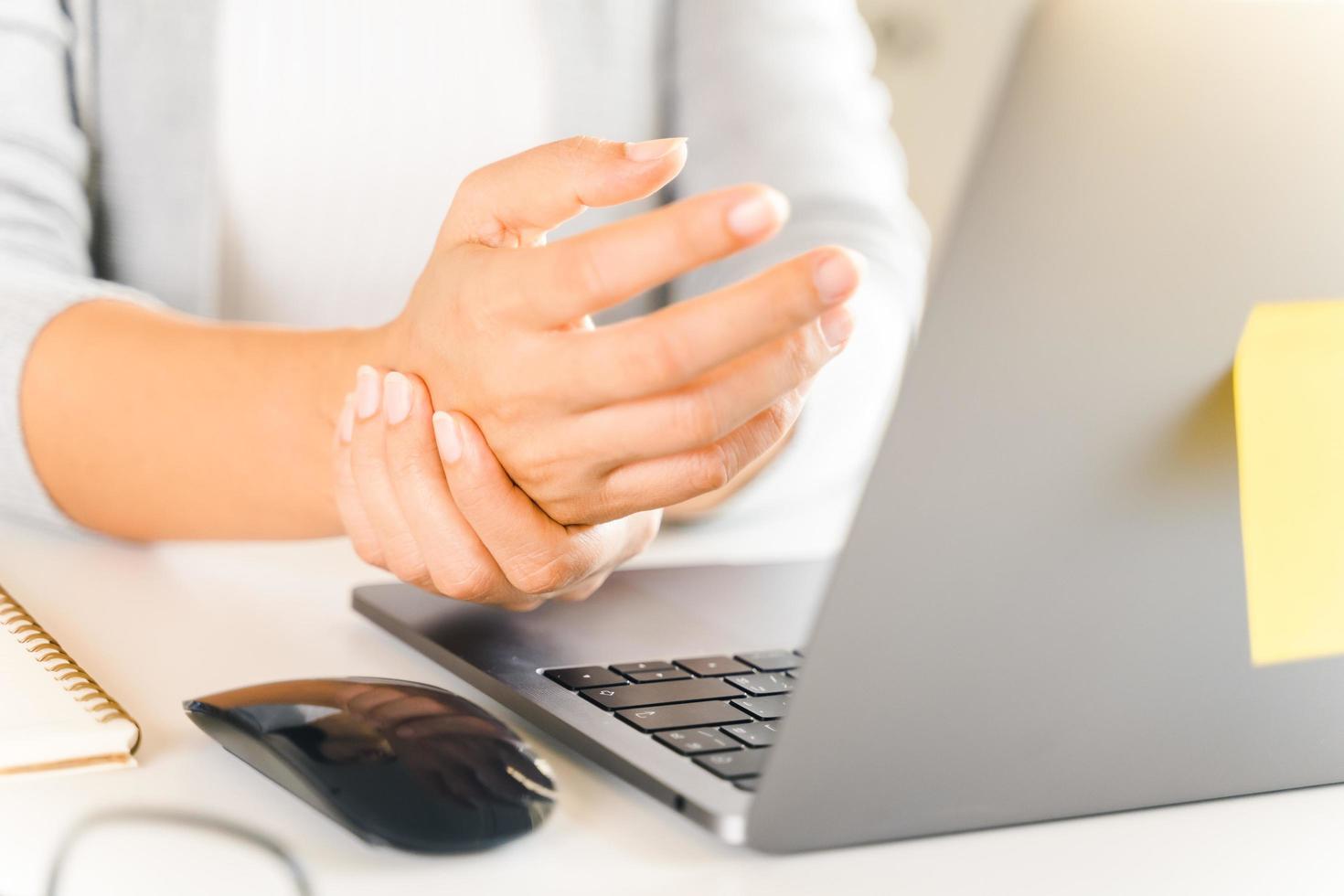 Closeup woman holding her hand pain from using computer long time. Office syndrome concept. photo