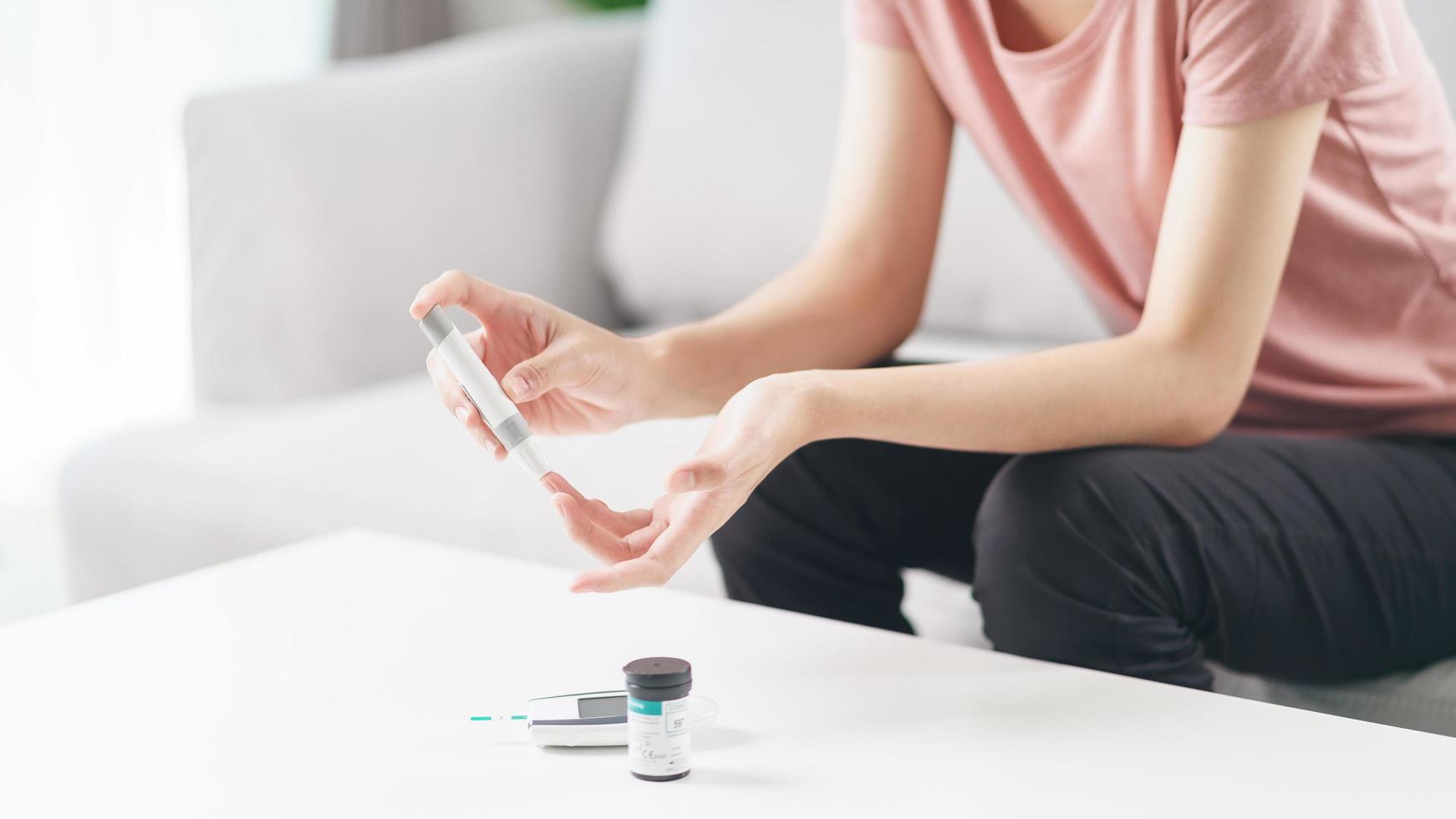 Asian woman using lancet on finger for checking blood sugar level by Glucose meter, Healthcare and Medical, diabetes, glycemia concept photo