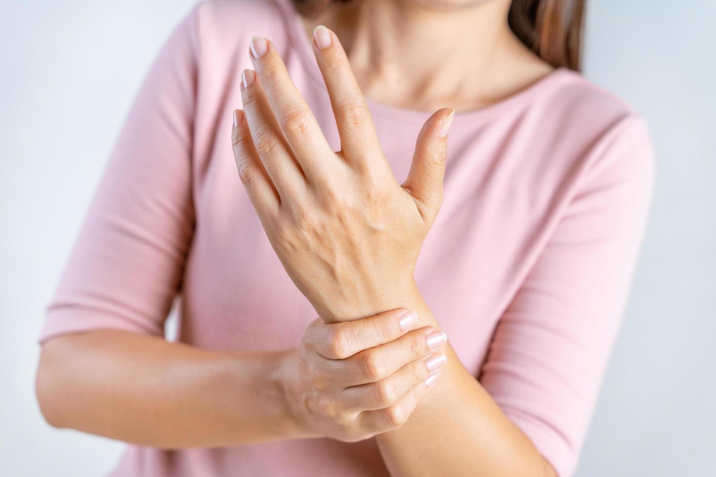 Closeup young woman holds her wrist on white background. hand injury, feeling pain. Health care and medical concept. photo