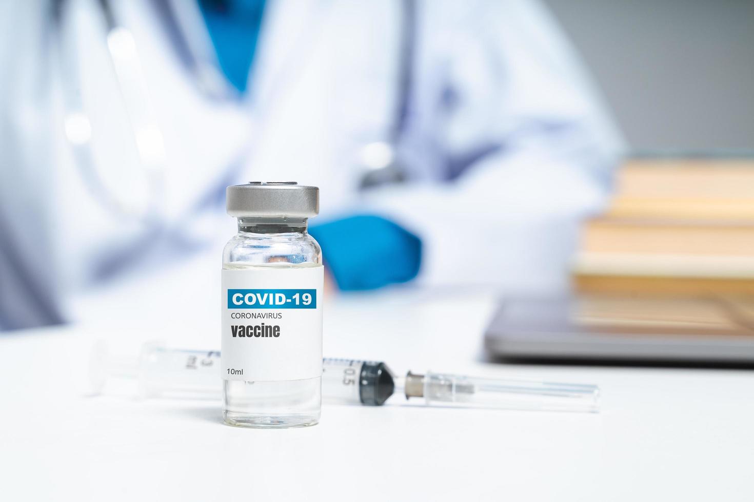 Covid-19 Coronavirus vaccine on the table with doctor or scientist on background. Covid-19 Coronavirus treatment concept. photo