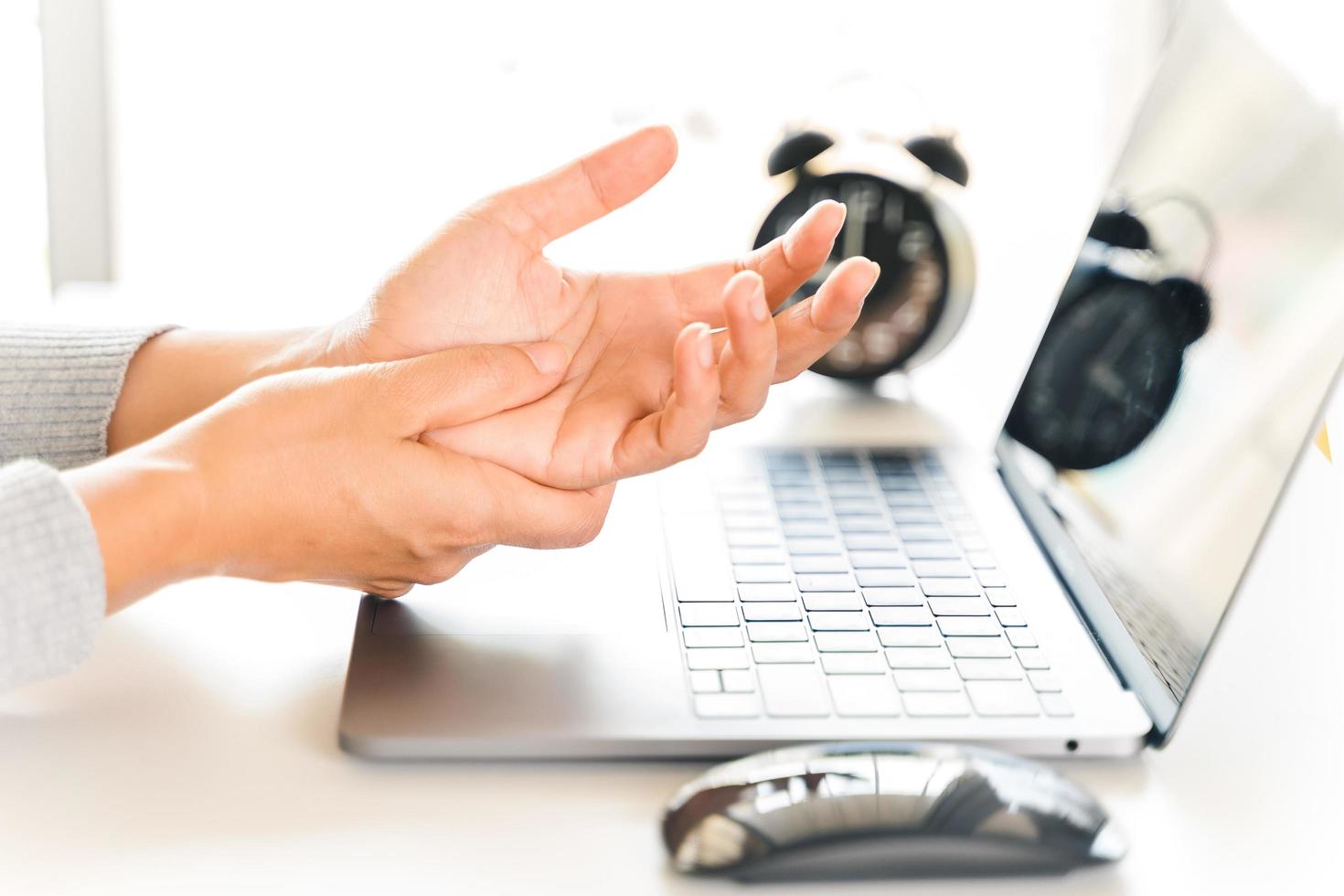 primer plano mujer sosteniendo su dolor en la mano por usar la computadora durante mucho tiempo. concepto de síndrome de oficina. foto