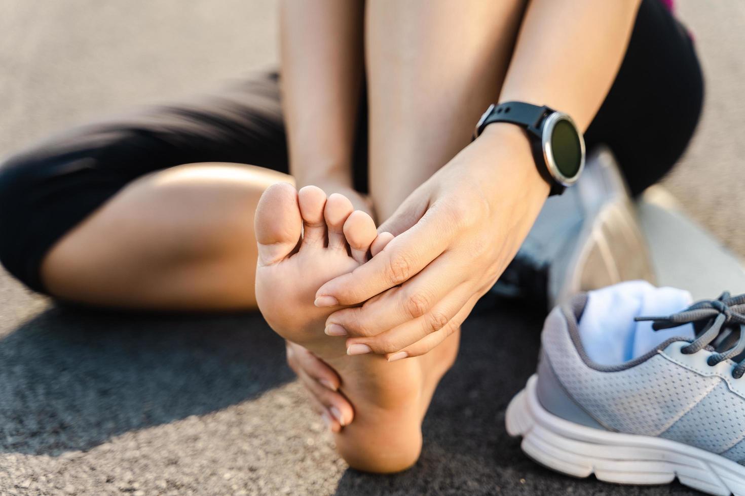 Running injury leg accident- sport woman runner hurting holding painful sprained ankle in pain. Female athlete with joint or muscle soreness and problem feeling ache in her lower body. photo