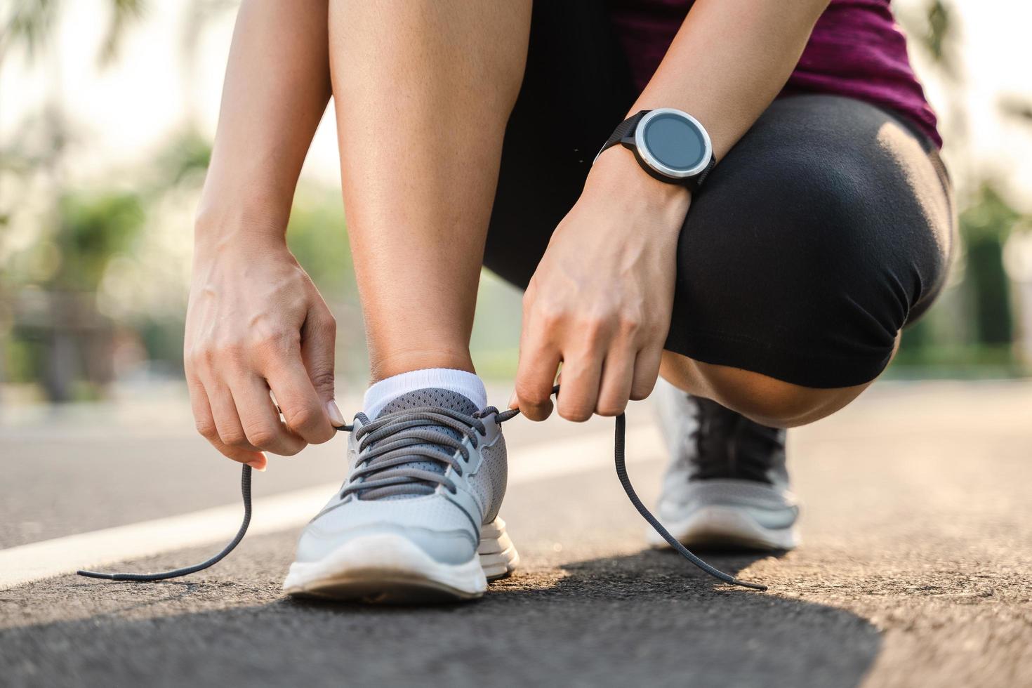 Primer plano del corredor de la mujer joven atando sus cordones. concepto de salud y fitness. foto