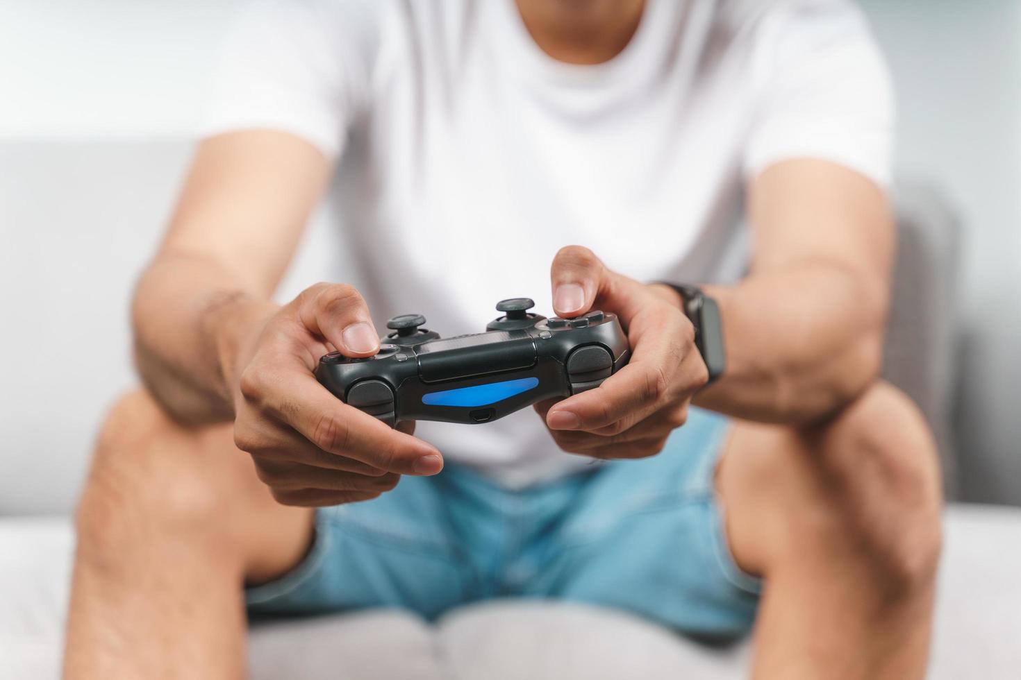 Hombre guapo joven emocionado sosteniendo controlador de joystick jugando videojuegos sentado en el sofá en casa foto