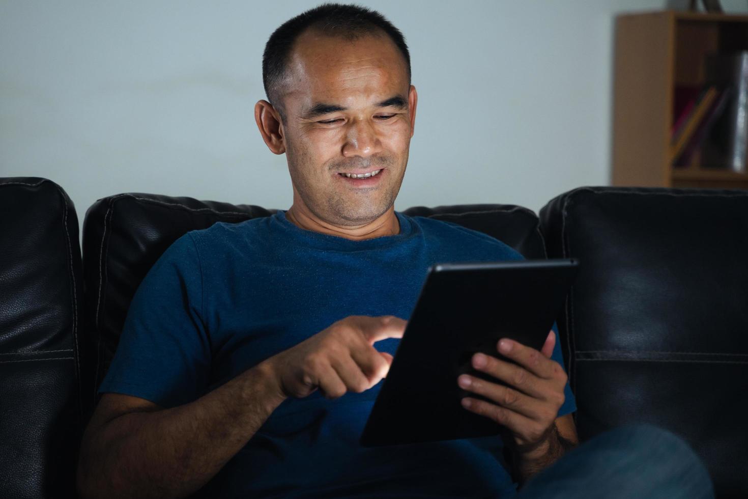 Man sitting on sofa, using tablet computer for work or relax at home. work from home concept. photo