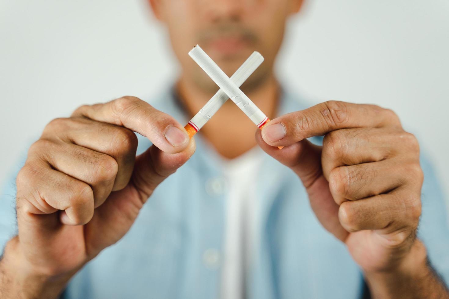 mano de hombre sosteniendo cigarrillos cruzados. concepto dejar de fumar, día mundial sin tabaco. foto