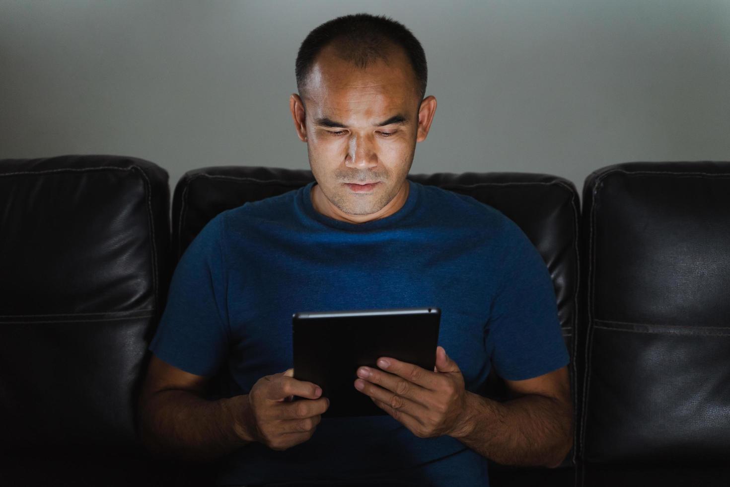 Man sitting on sofa, using tablet computer for work or relax at home. work from home concept. photo