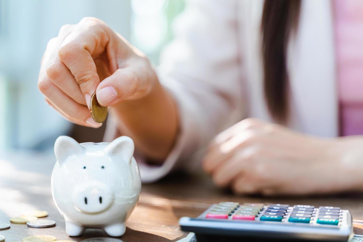 Closeup of business woman hand putting money coin into piggy bank for saving money. saving money and financial concept photo