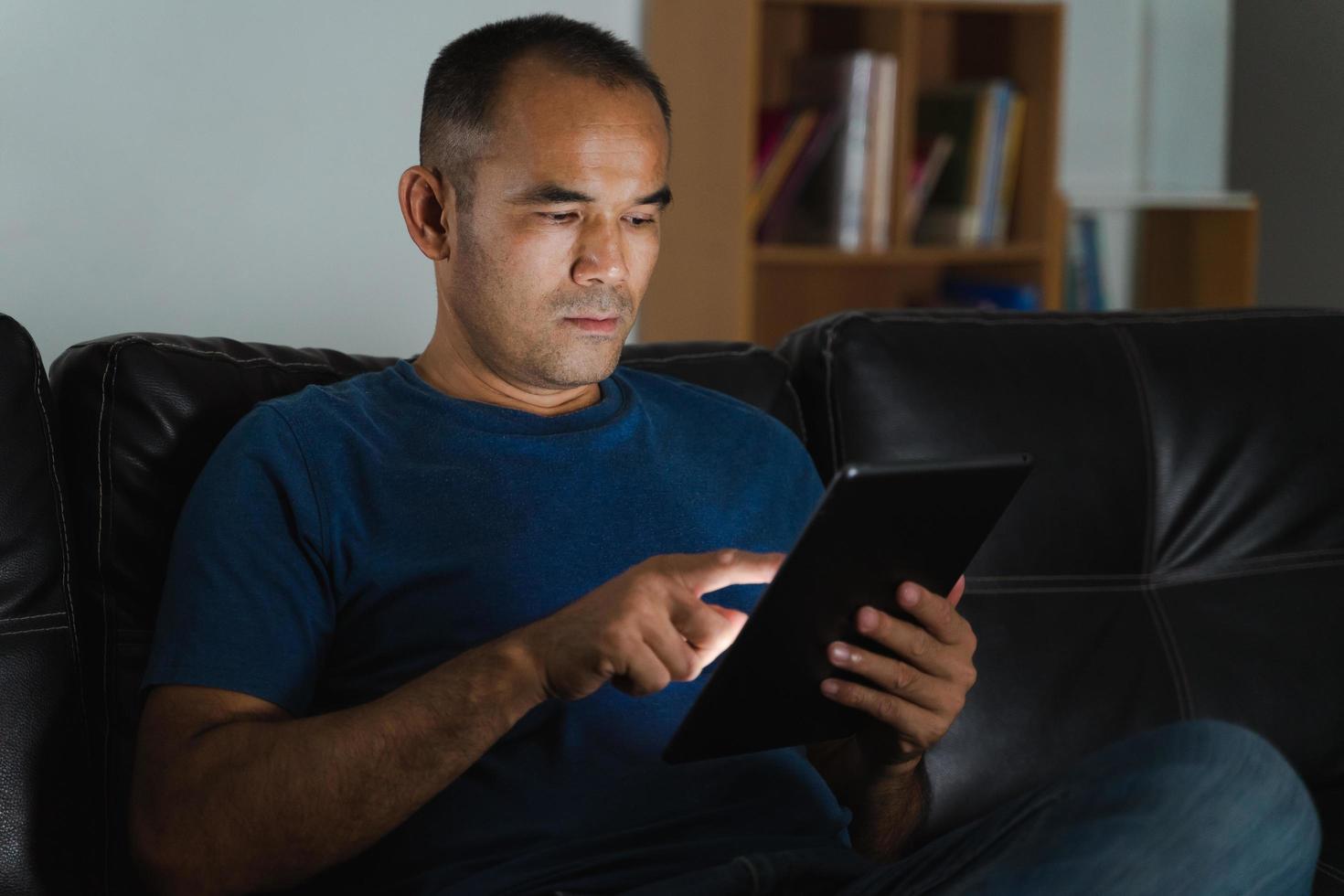 Man sitting on sofa, using tablet computer for work or relax at home. work from home concept. photo