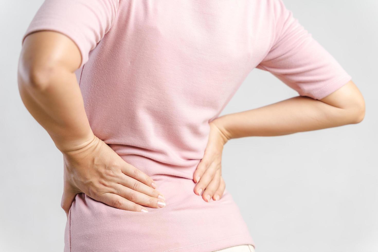 Young woman feeling pain in her back on white background. Healthcare and medical concept. photo