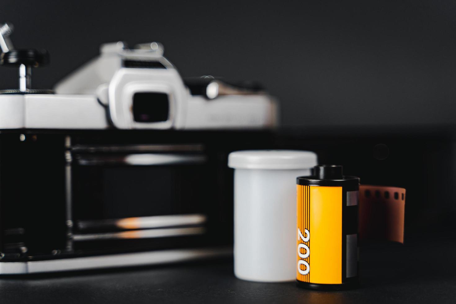 Old SLR film camera and a roll of film on black background, Photography Concept. photo