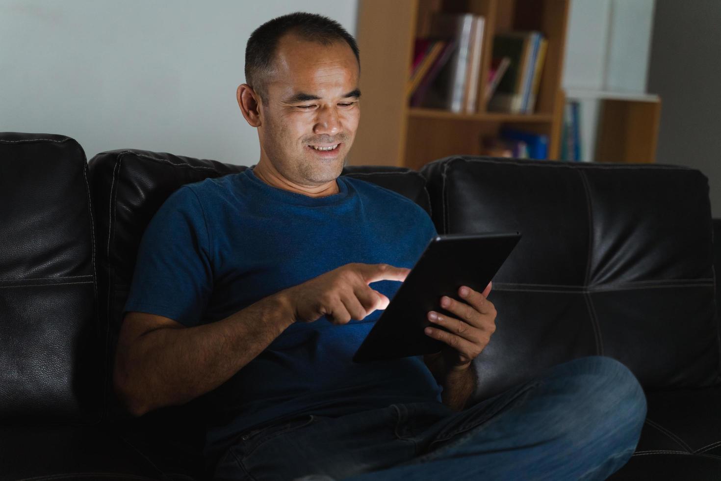 Man sitting on sofa, using tablet computer for work or relax at home. work from home concept. photo