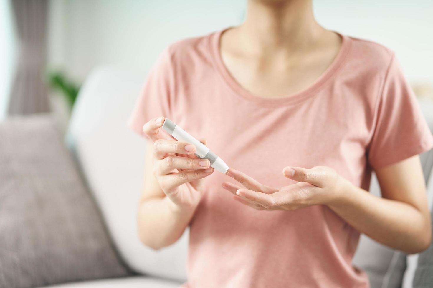 Asian woman using lancet on finger for checking blood sugar level by Glucose meter, Healthcare and Medical, diabetes, glycemia concept photo