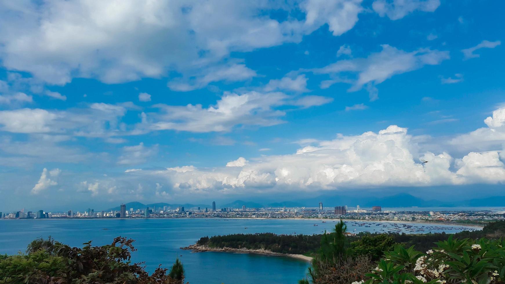 Blue sky with white clouds over a city near the ocean photo