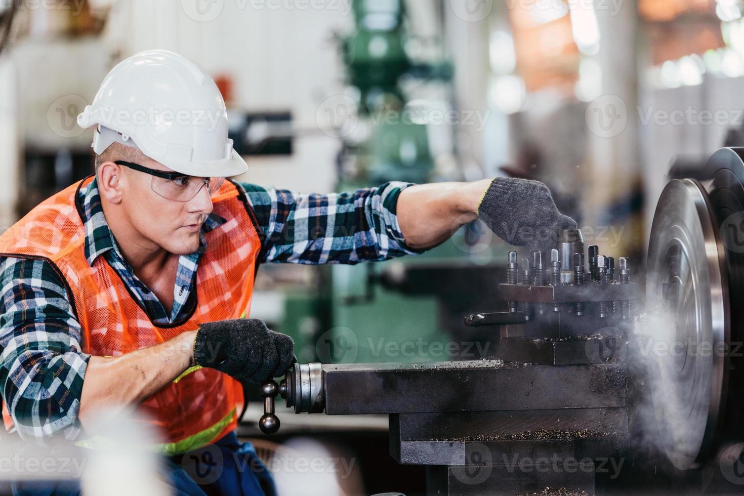 Engineer metalworker working on lathe machine photo