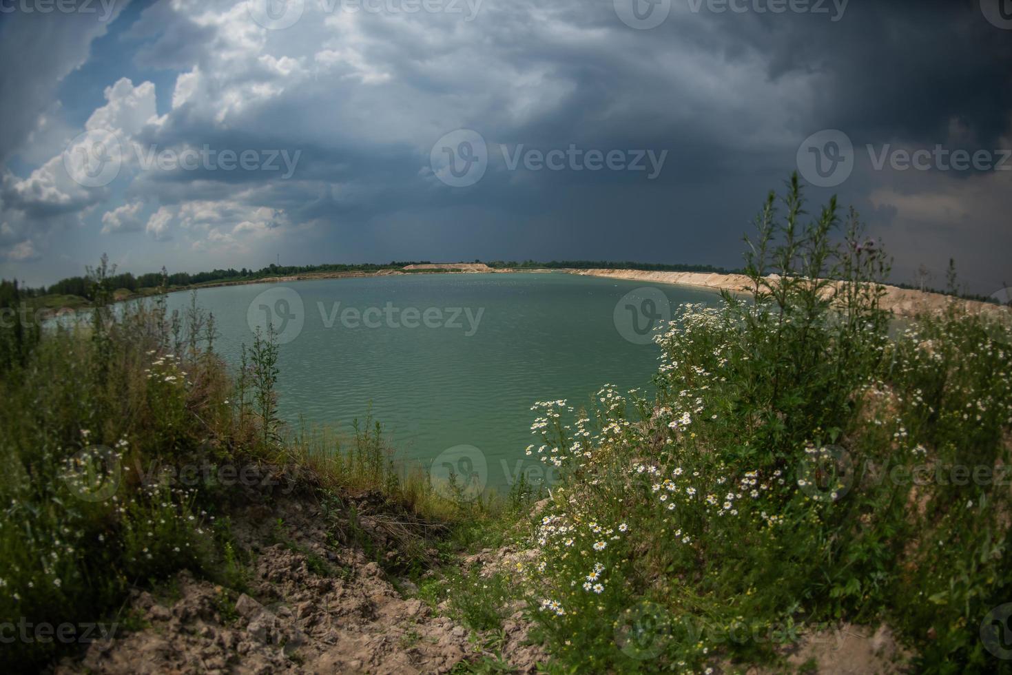 Panorama of a blue lake with a sandy shore. Lake view. Overcast sky. photo