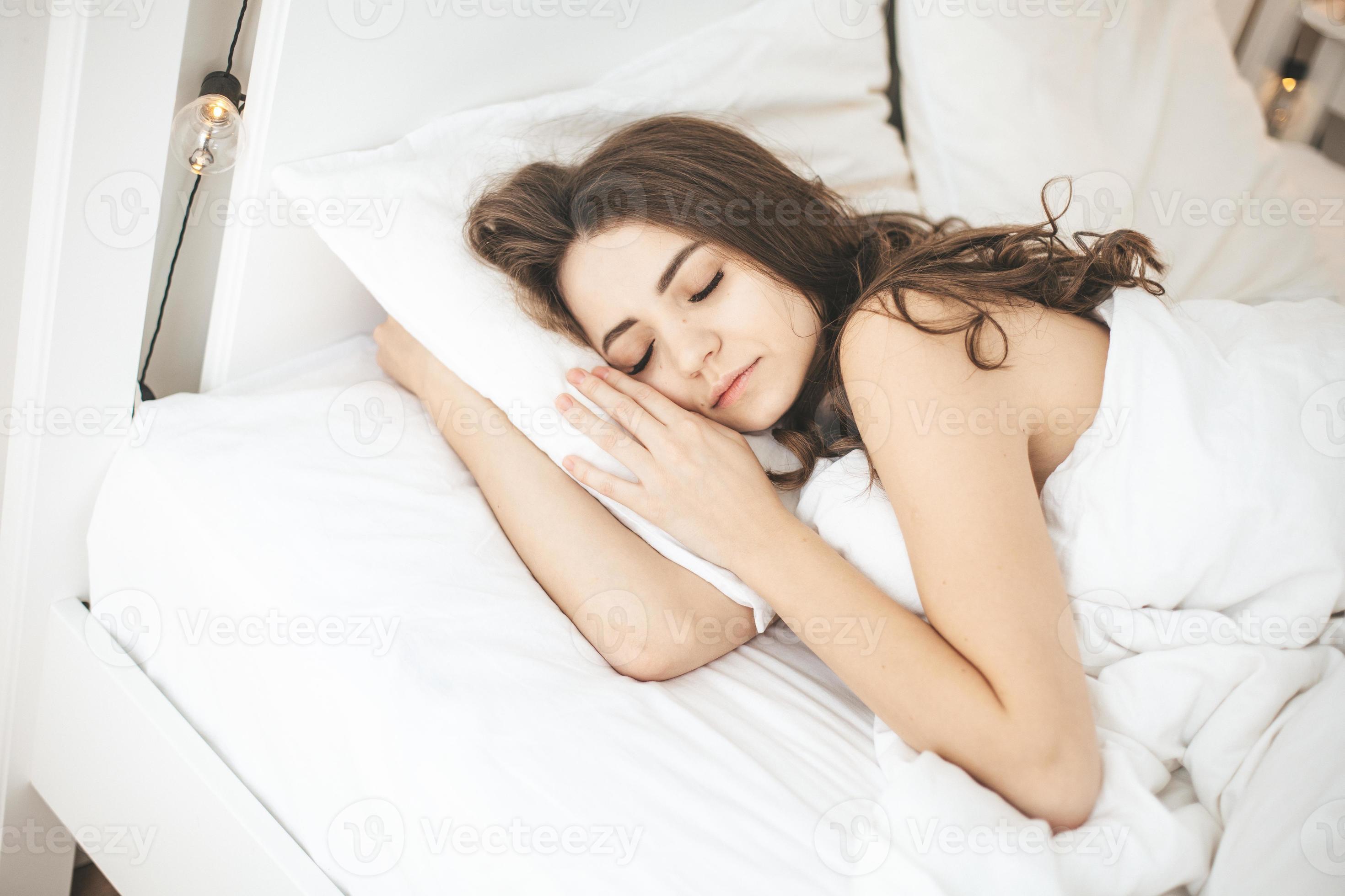 Woman sleeping peacefully in comfortable bedroom with fresh white sheets