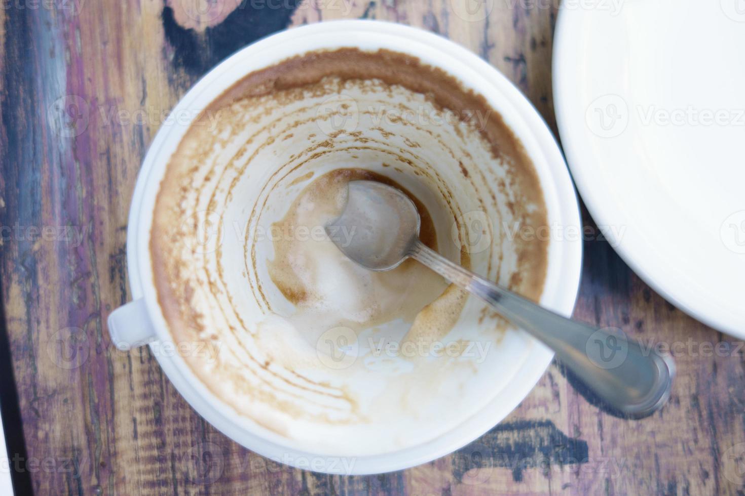 white cup with coffee leftovers on table photo