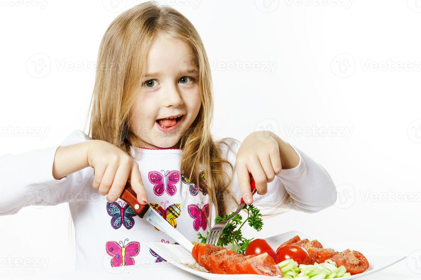 Cute little girl with plate of fresh vegetables photo