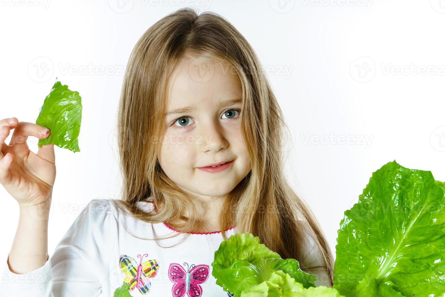 linda niña posando con ensalada de hojas frescas foto