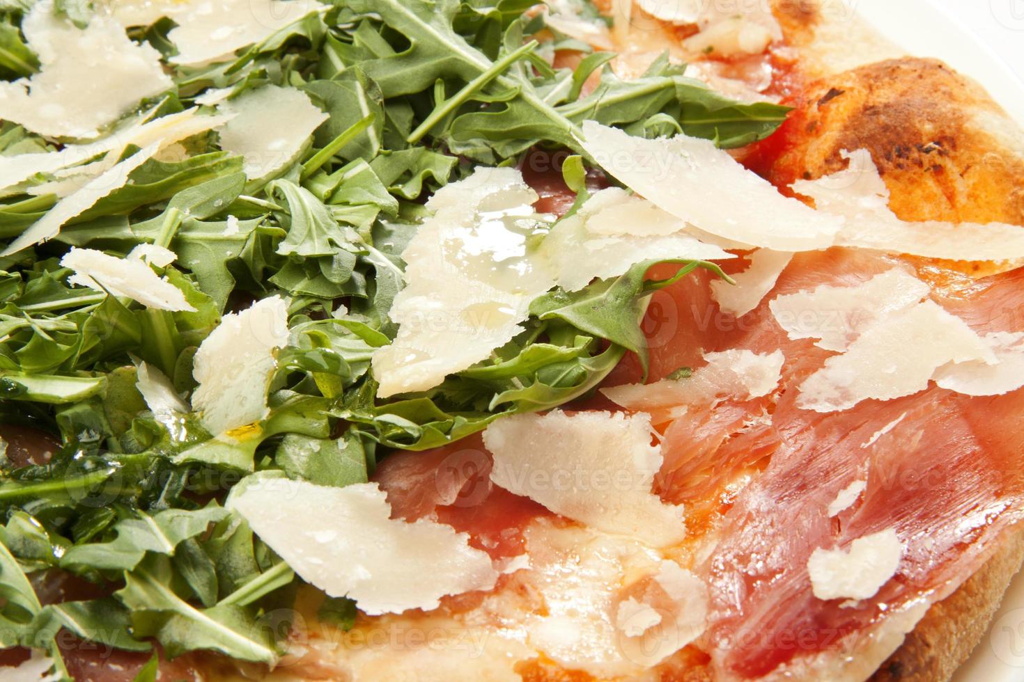 pizza with parmesan cheese, arugula and prosciutto closeup photo