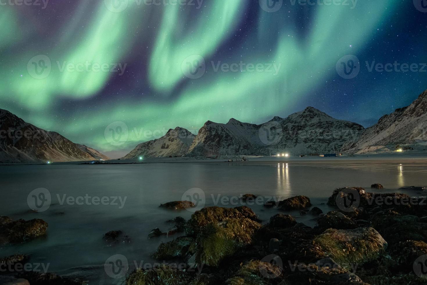 Aurora borealis with stars over mountain range on coastline photo