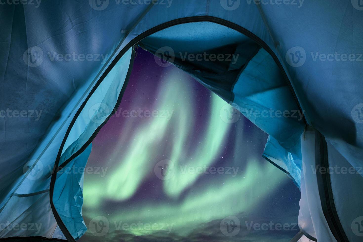 Inside of blue tent camping with aurora borealis flying in the sky photo