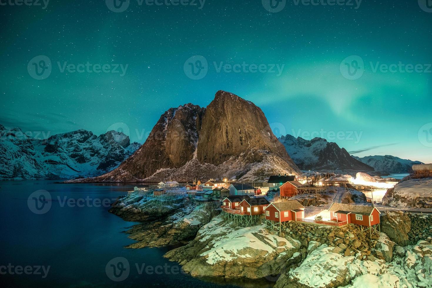 Aurora boreal sobre la montaña con pueblo de pescadores en Hamnoy foto