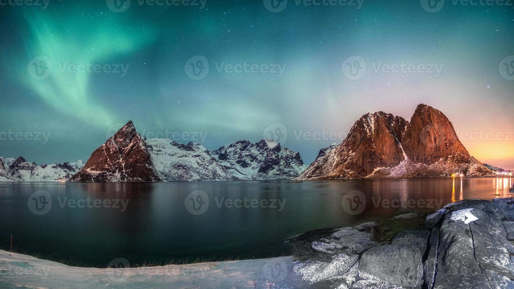 Panorama de la aurora boreal sobre la montaña en el pueblo pesquero de Hamnoy en invierno foto