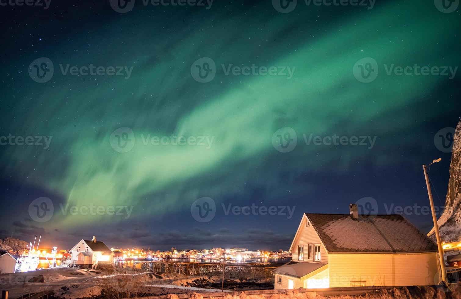 Aurora boreal bailando sobre un pueblo escandinavo foto