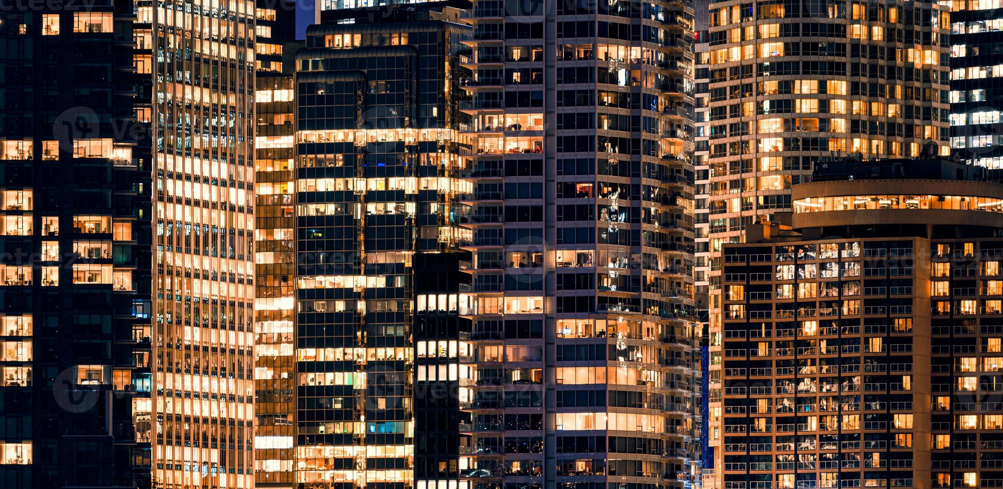 Facade windows of illuminated modern skyscraper with office building at night photo