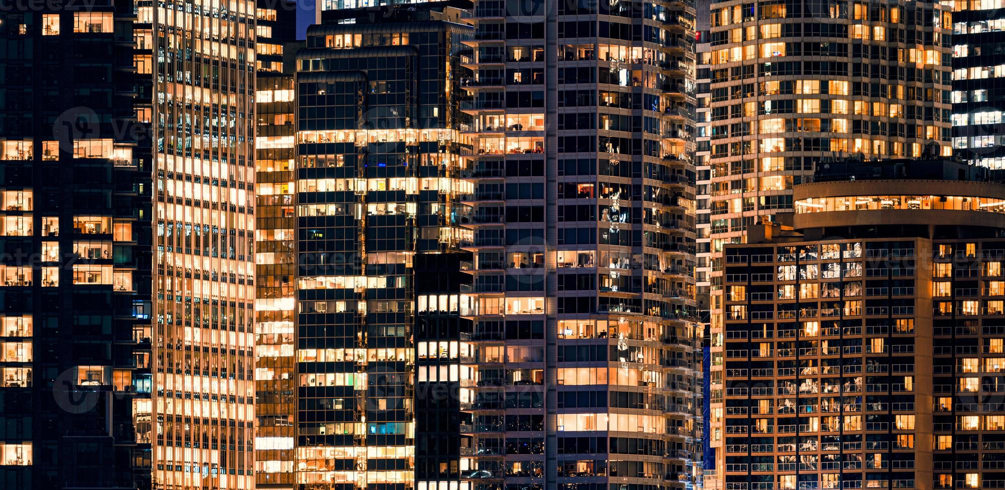 Ventanas de la fachada del rascacielos moderno iluminado con edificio de oficinas en la noche foto