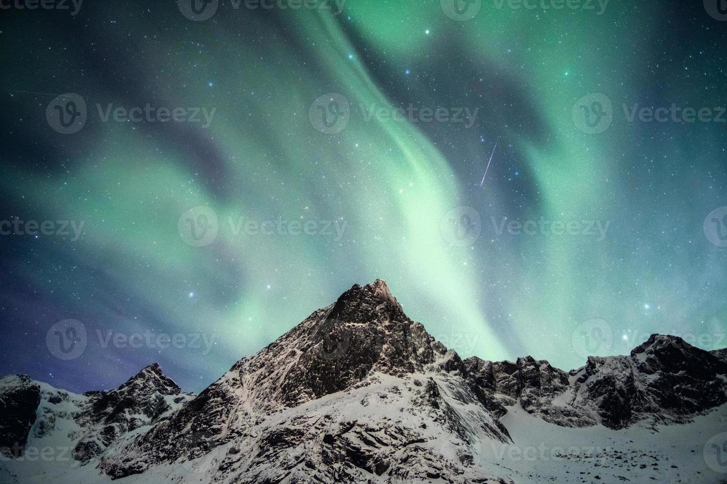 monte nevado con auroras boreales bailando con estrella fugaz foto