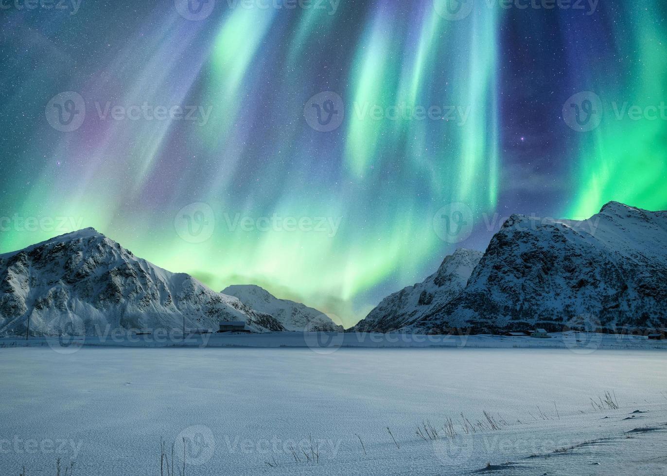 Aurora boreal, auroras boreales arriba en la montaña nevada en la playa de Skagsanden en las islas Lofoten foto