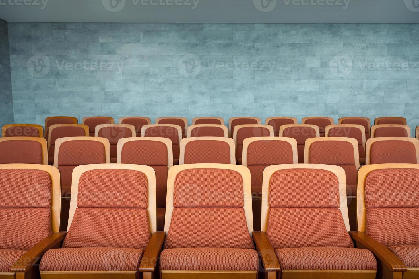 Fila de asientos de teatro marrón y paredes de mármol en auditorio foto