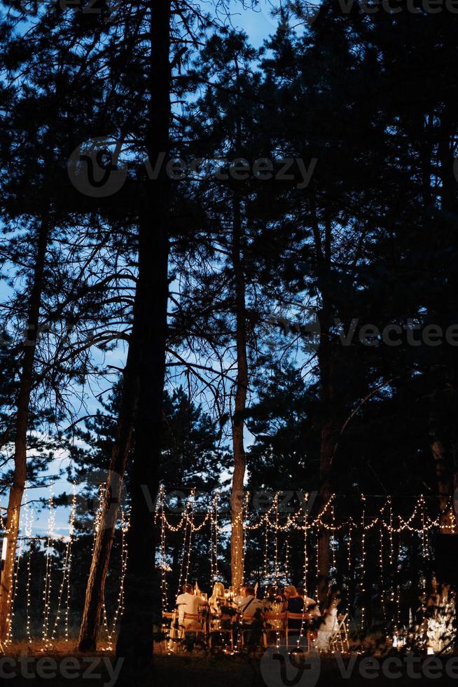 Área para banquetes de bodas en un bosque de pinos con un arco contra el fondo para varias personas foto