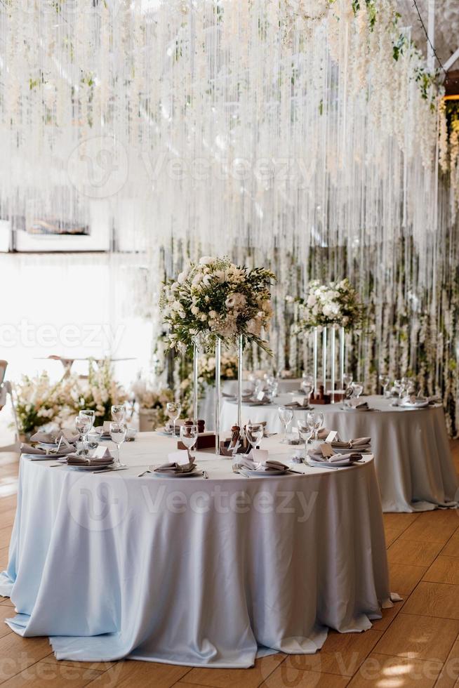 el presidium de los recién casados en el salón de banquetes del restaurante está decorado con velas y plantas verdes foto