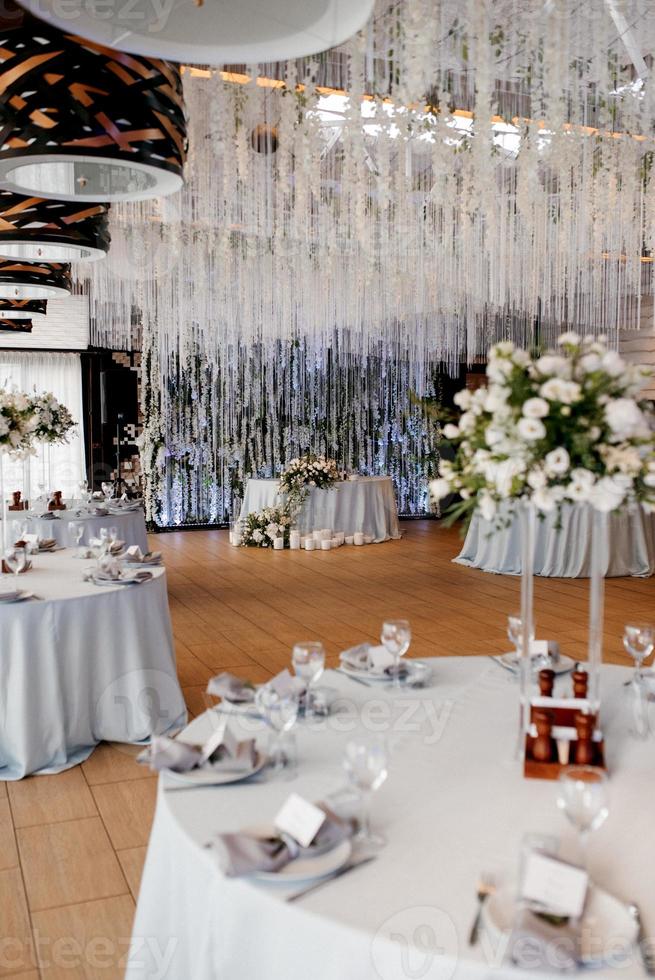 el presidium de los recién casados en el salón de banquetes del restaurante está decorado con velas y plantas verdes foto