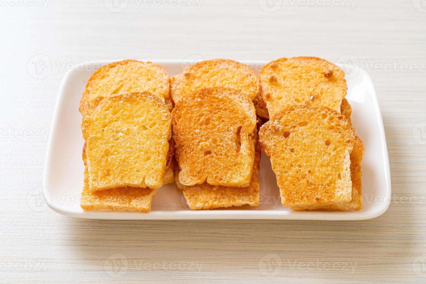 Baked crispy bread with butter and sugar on plate photo