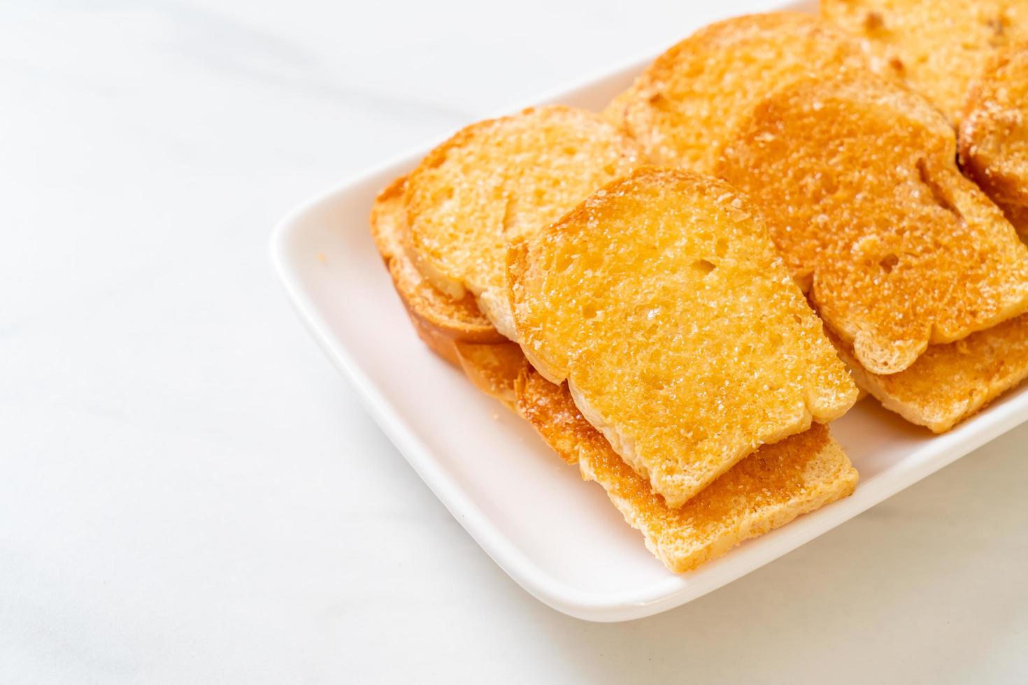 Baked crispy bread with butter and sugar on plate photo